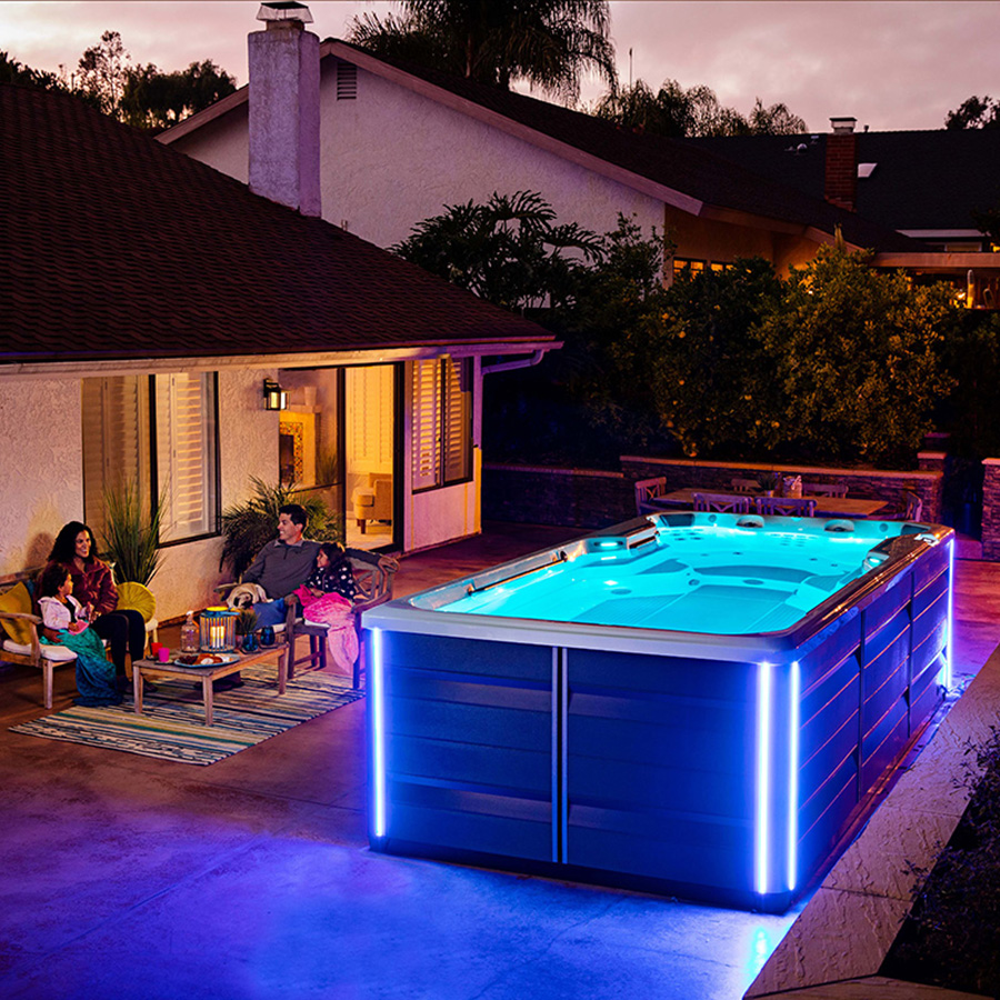 Endless Pools SwimCross X500 AlpineWhite Mocha Lit Up At Night With Family Sitting Nearby