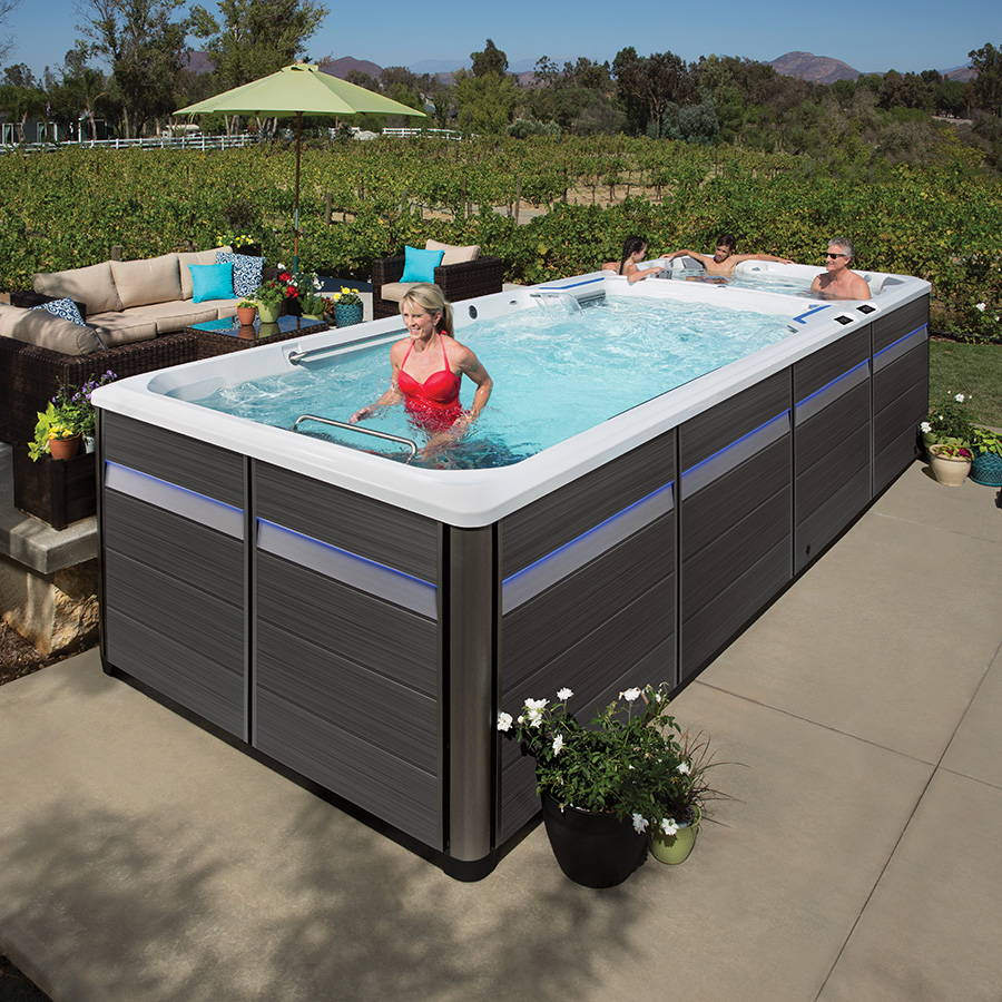Woman using treadmill while family relaxes in Endless Pools E2000 Swim Spa
