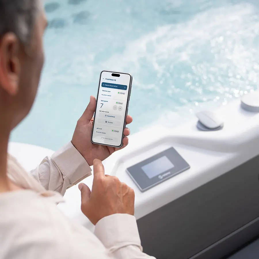 Man using HotSpring App for Freshwater IQ near a hot tub