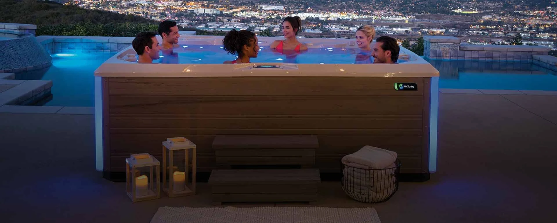 Inground pool with illuminated patio at dusk